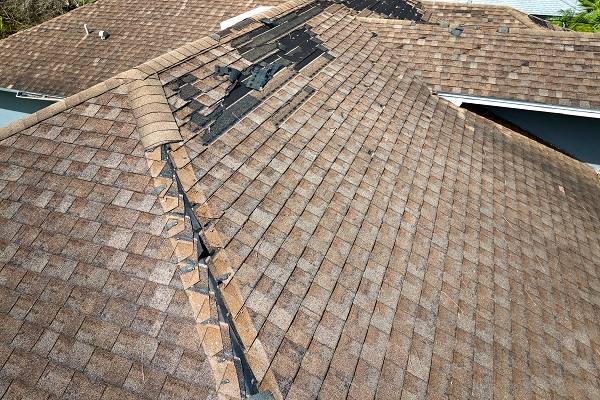 Wind Damaged House Roof With Missing Asphalt Shingles After Hurricane Ian In Florida. Repair Of Home Rooftop Concept